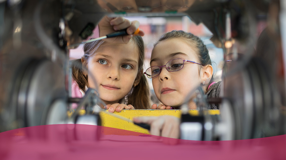3 Ways to Highlight Career Paths to K-8 Students Two young girls observing the inside of a mechanical device.