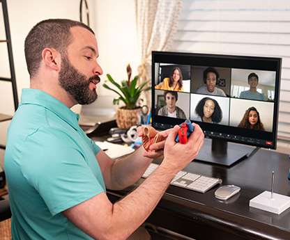 A virtual teacher in his home office gives a live video conferencing lesson on science