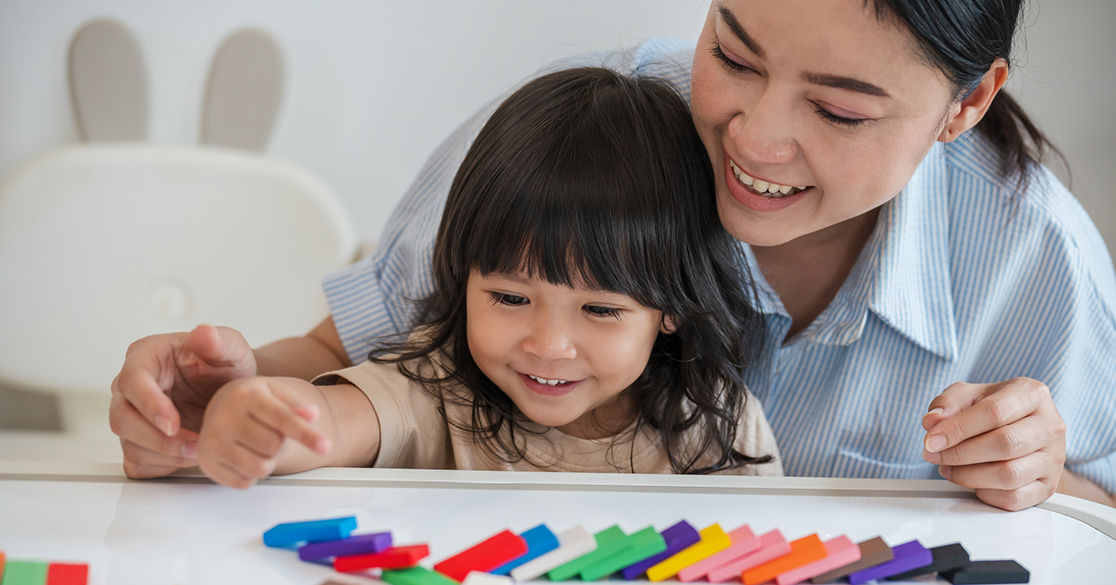 A parent and young child participate in a hands-on science activity.