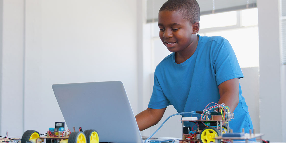Student works on a laptop while building a robotics project, demonstrating hands-on career and technical education through digital learning.