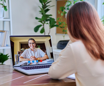 A student is on a video conference call with her teacher on a laptop.